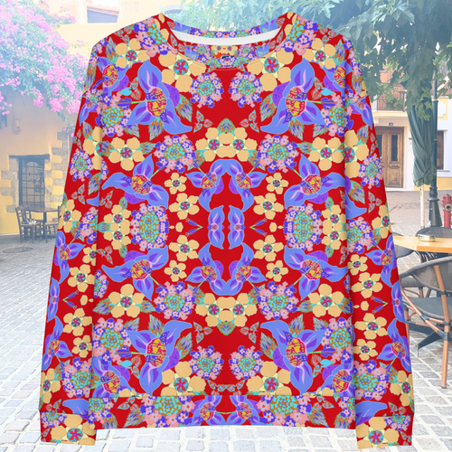 Front flat view of a colorful red, yellow and blue floral patterned sweatshirt in front of a village outdoor background.