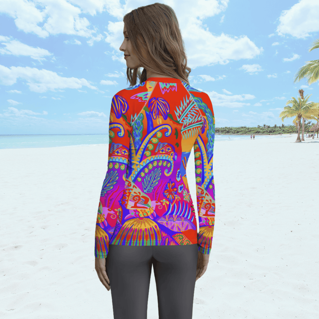 Back view of female standing on a beach. She is wearing a a long-sleeved rash guard top with a vibrant, colorful tropical scene with insects. The top features a red base with blue, orange, purple, and yellow floral and abstract patterns.