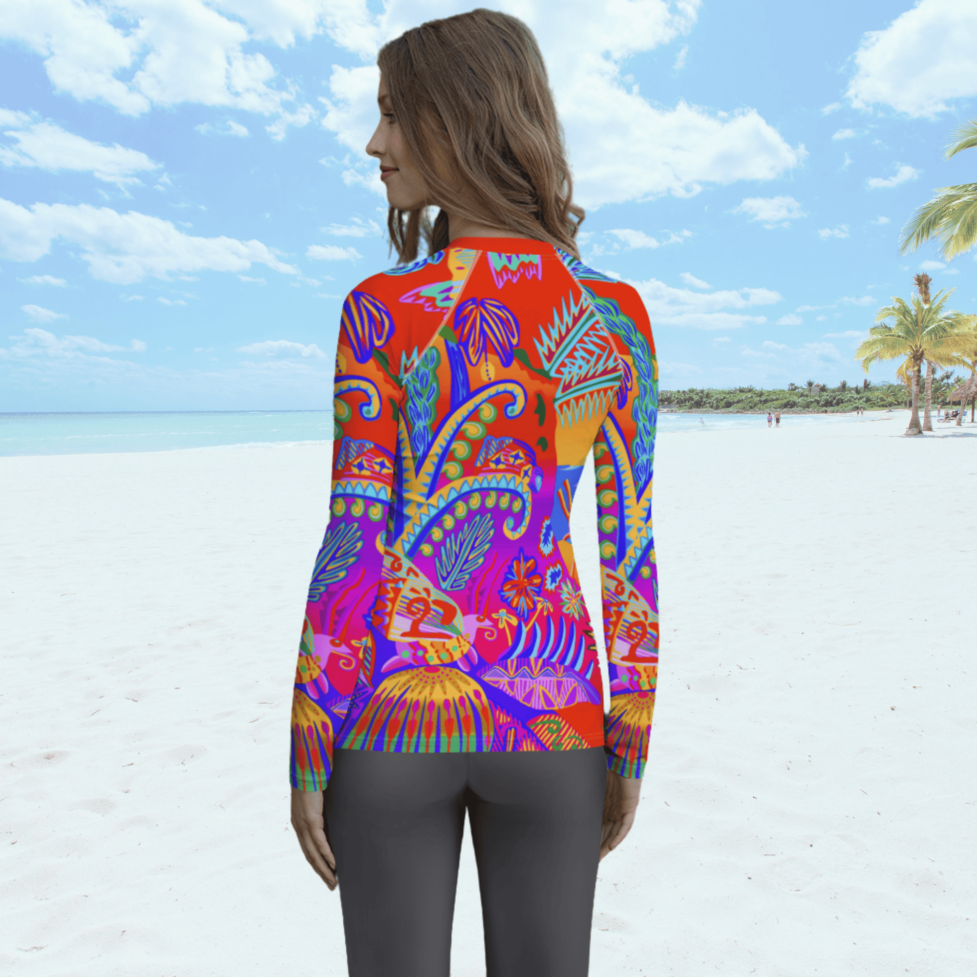 Back view of female standing on a beach. She is wearing a a long-sleeved rash guard top with a vibrant, colorful tropical scene with insects. The top features a red base with blue, orange, purple, and yellow floral and abstract patterns.