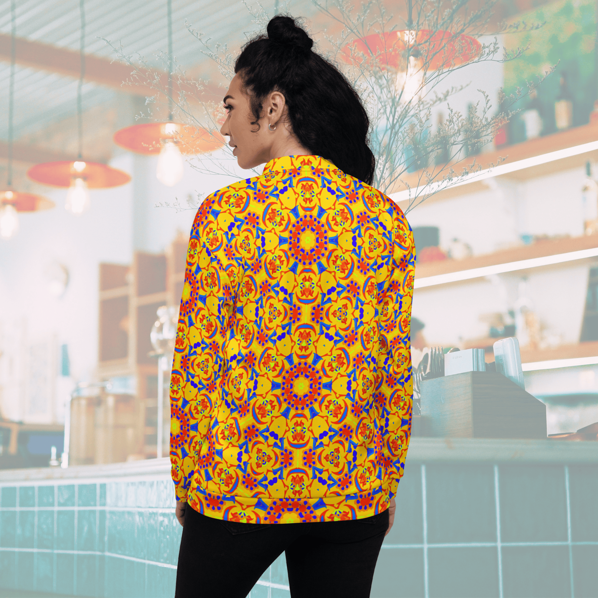 Rear view of a woman showcasing the back design of a yellow bomber jacket adorned with large, symmetrical red, orange, and blue mandala art circles.
