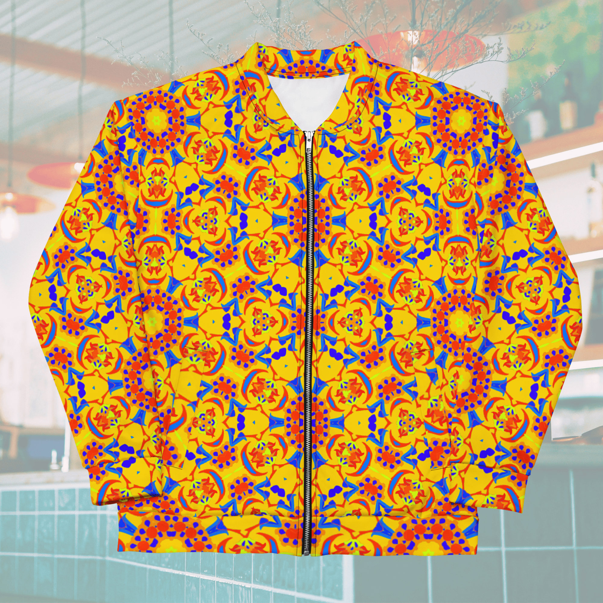 Front flat-lay view of a unisex yellow bomber jacket with a white collar lining and metallic zipper, showcasing an all-over symmetrical tile pattern in bold blue, red, and orange.
