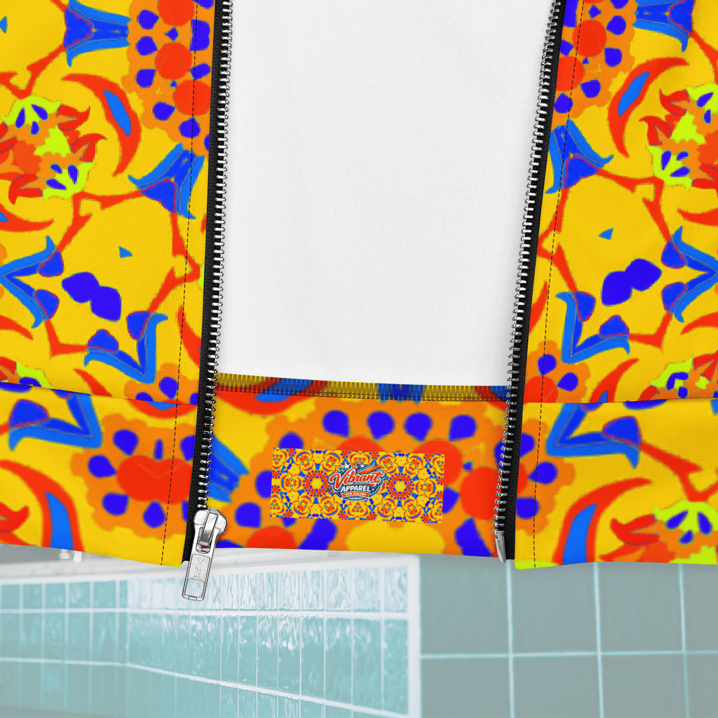 Close-up macro shot of the open metallic zipper on a yellow patterned jacket, revealing a white inner lining and an internal fabric clothing tag that reads "Vibrant Apparel" set against an orange geometric pattern.